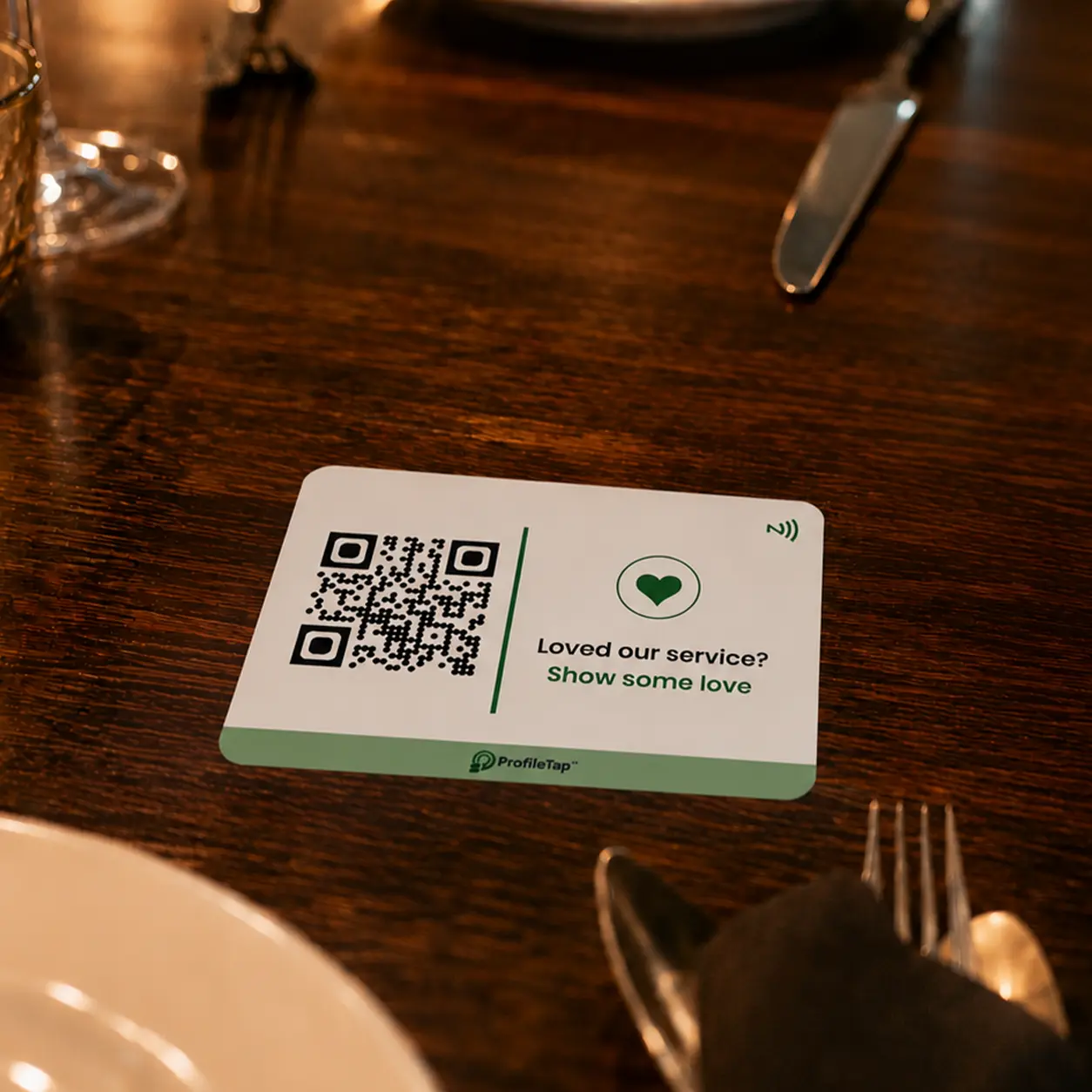 A ProfileTap NFC table tap card standing on a café counter beside a phone.